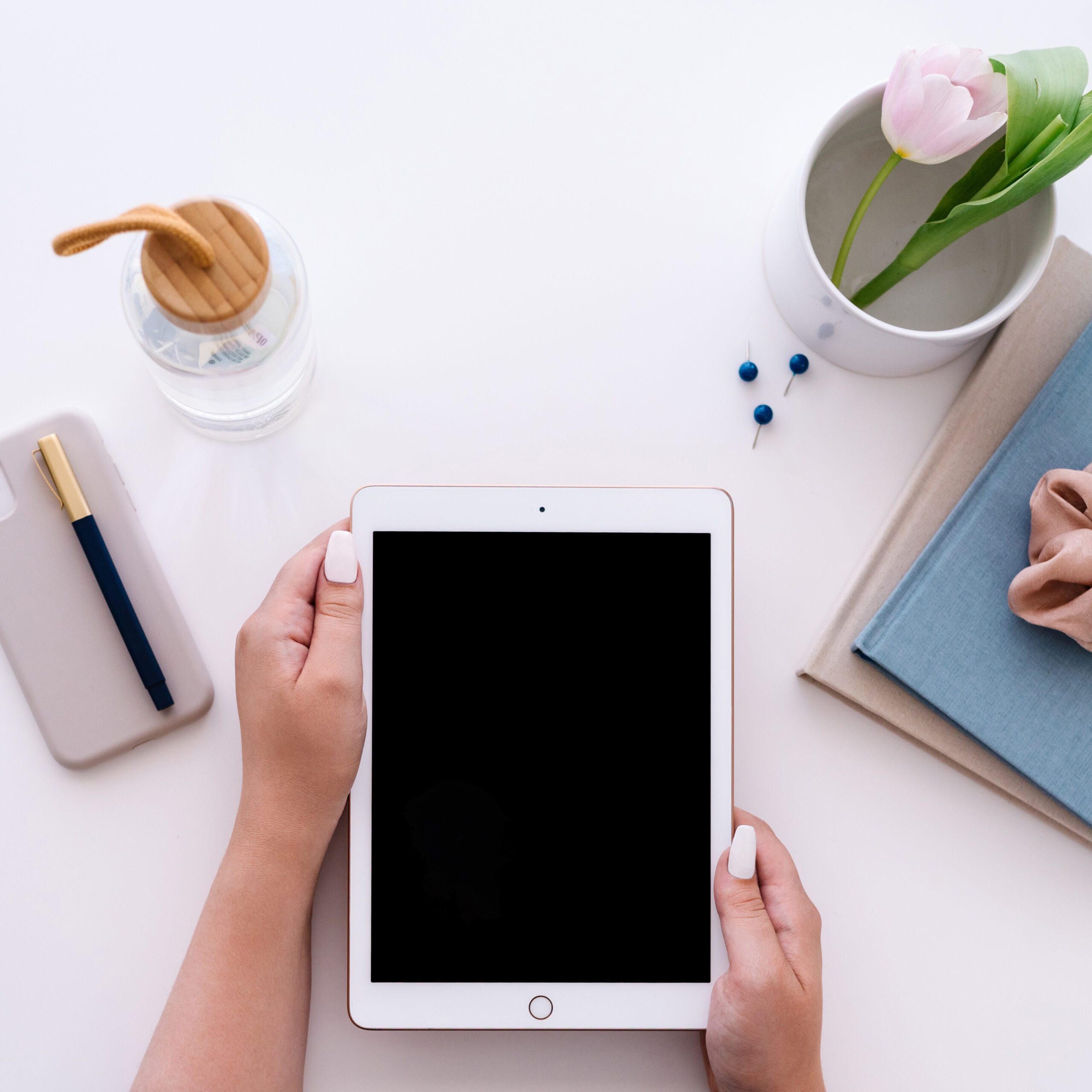 hands holding tablet with planner and notebook on desk