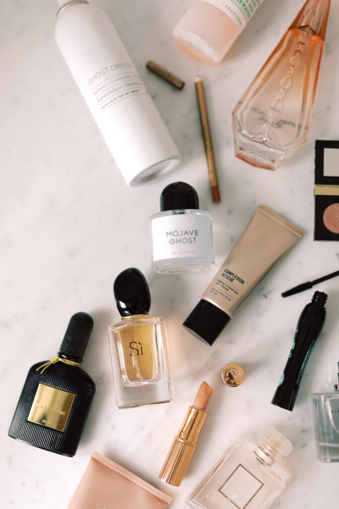 Makeup essentials and luxury perfumes on white marble, featuring popular lipstick shades, mascara, skincare, and cosmetics.