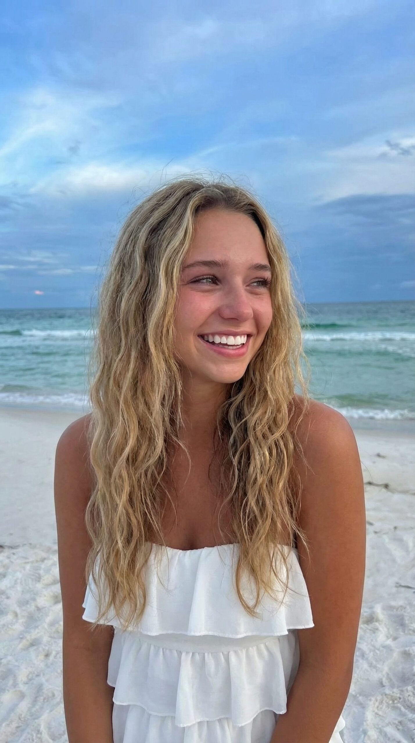 woman with glowing skin smiling at the beach summer sun protection
