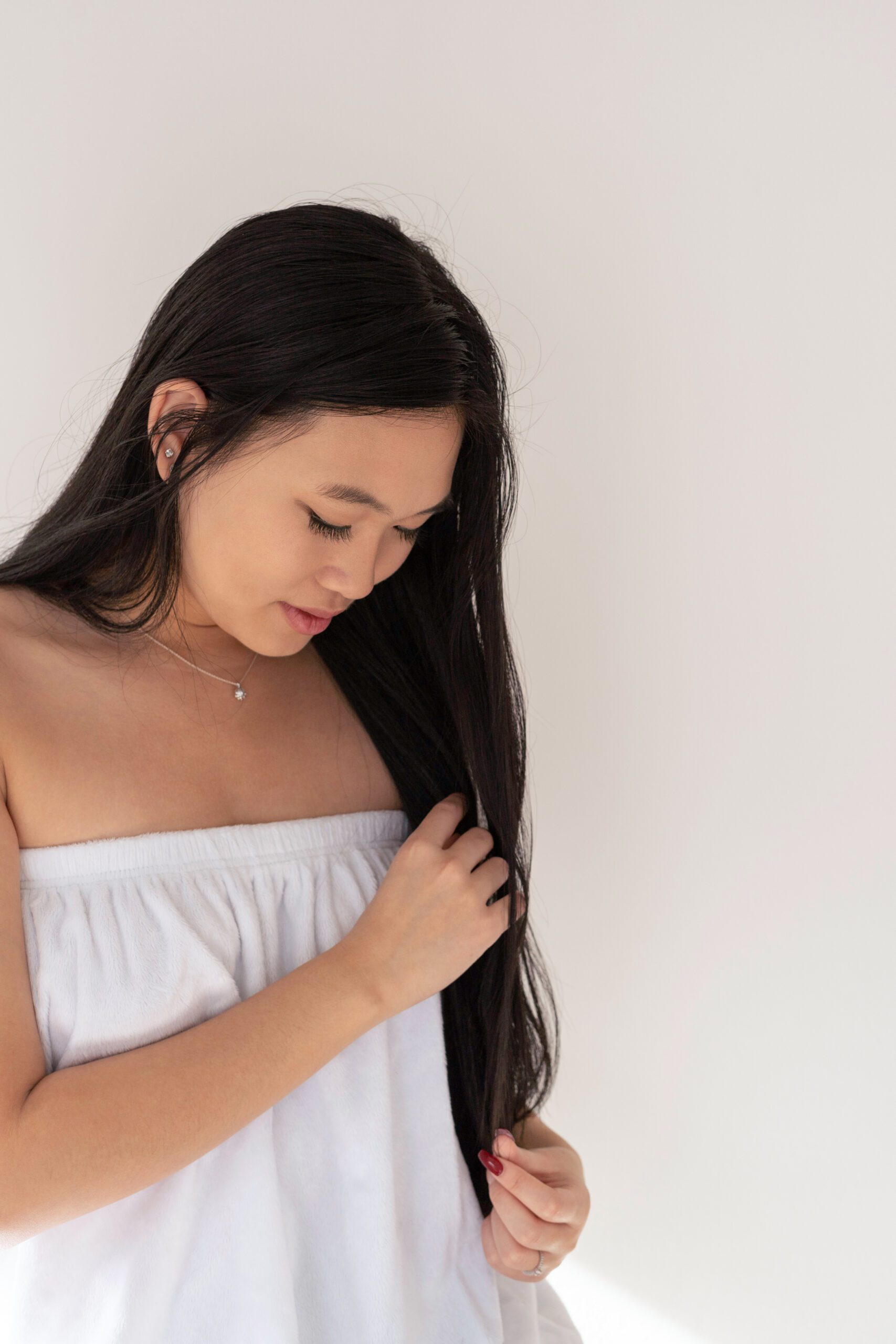 woman touching long dark hair in white top