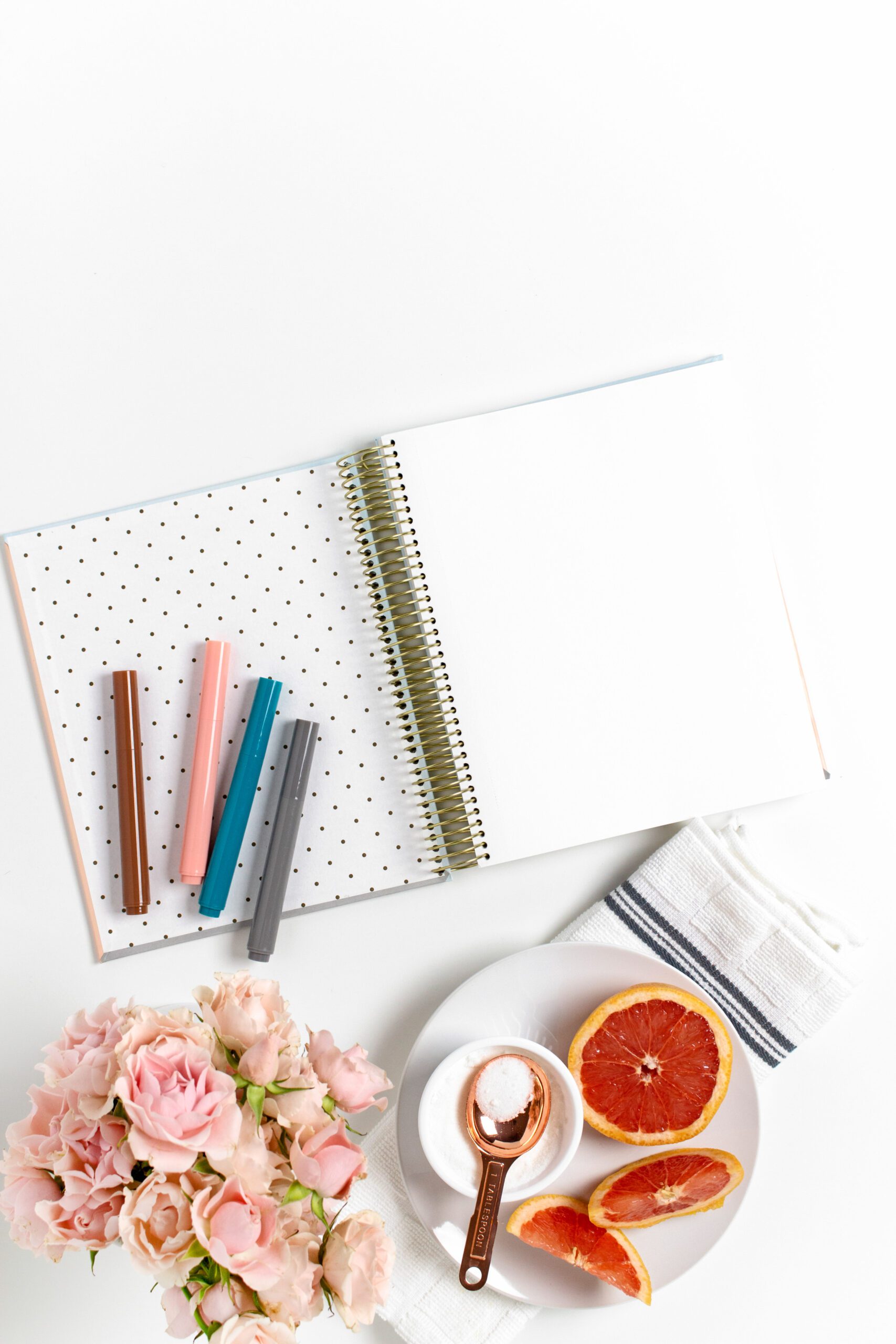 planner notebook with grapefruit slices and colored pens on white desk