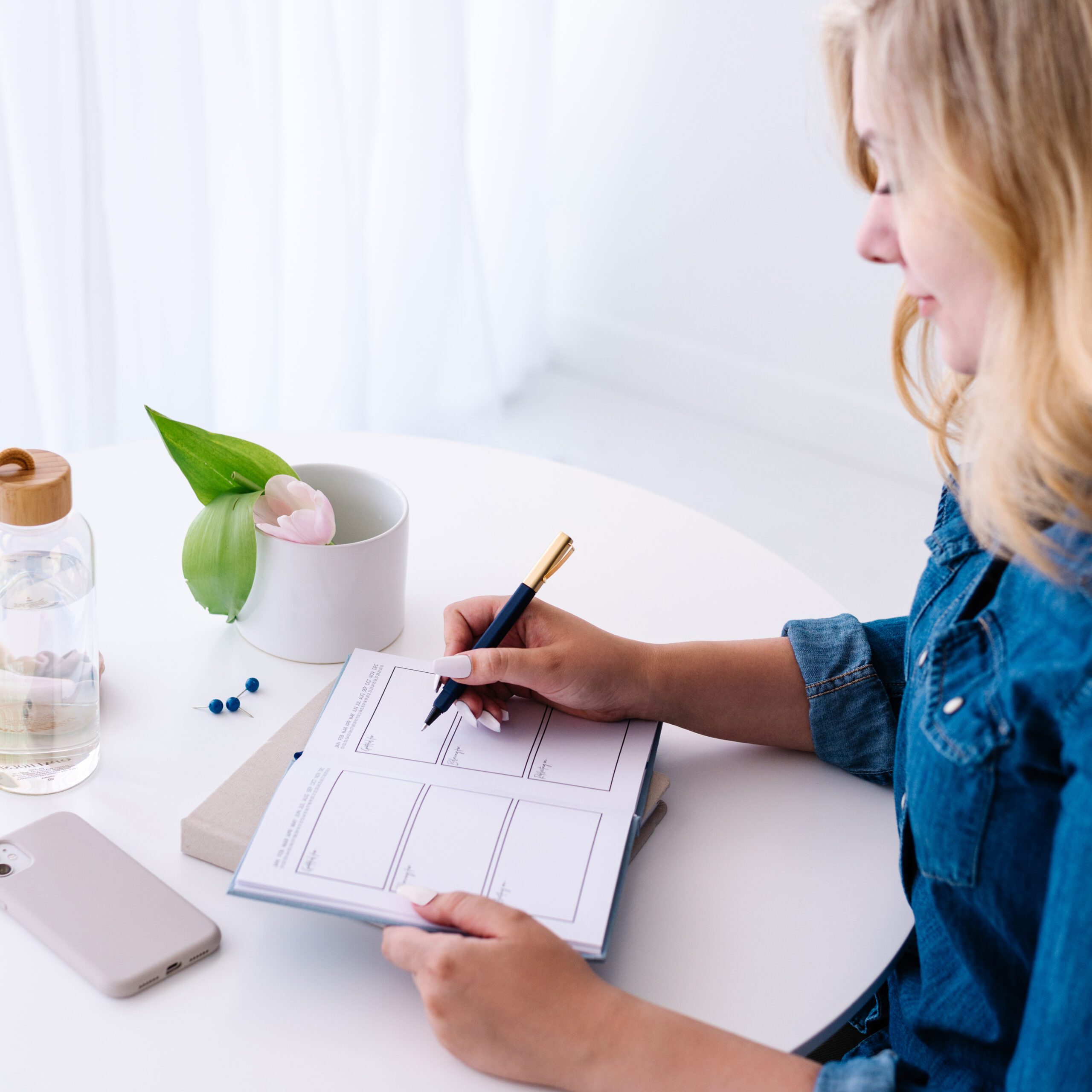 woman writing in planner at white desk morning routine planning