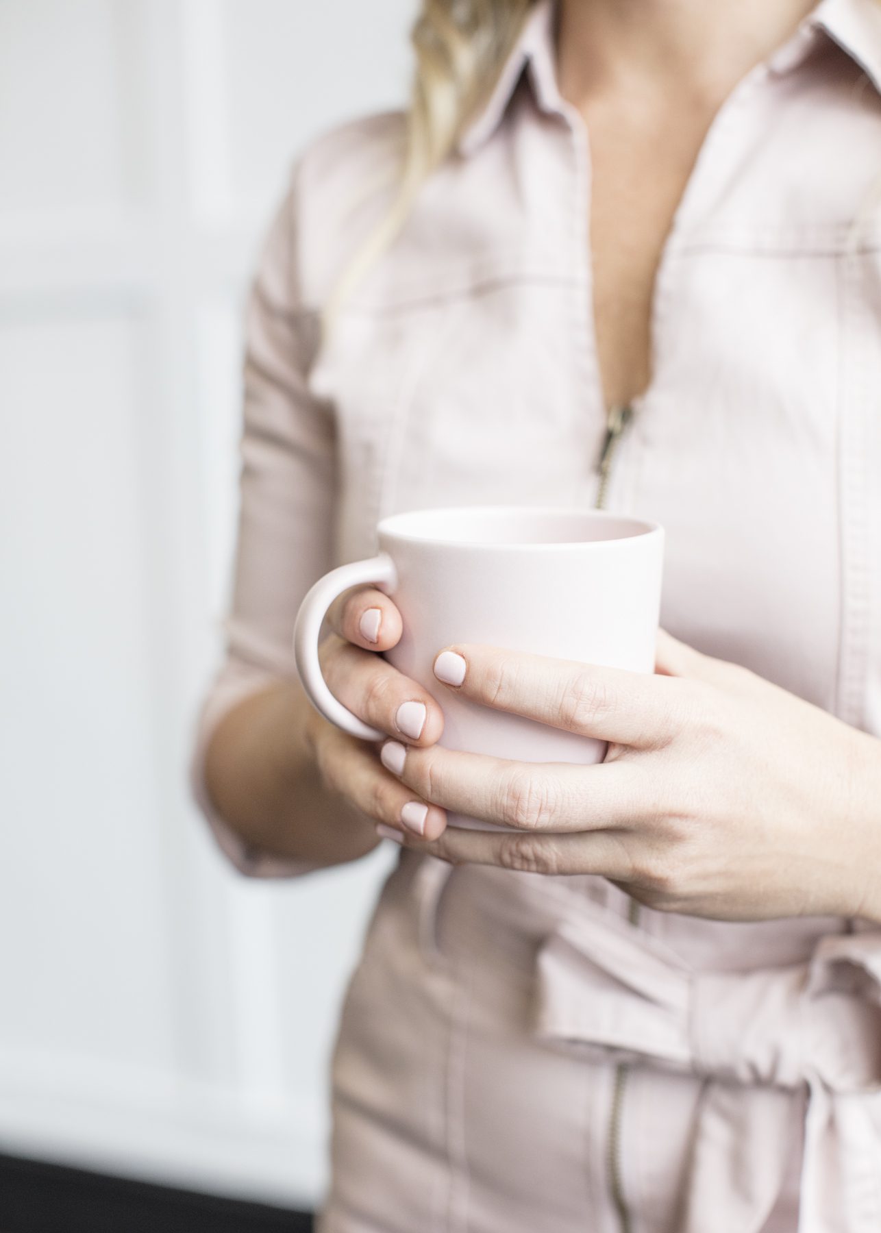 woman holding coffee mug in neutral outfit