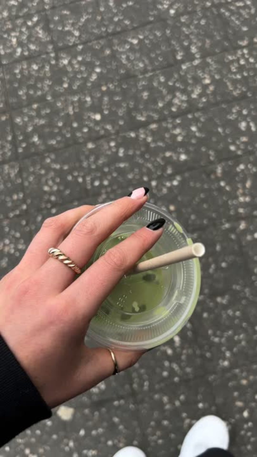 hand holding matcha drink while walking outside
