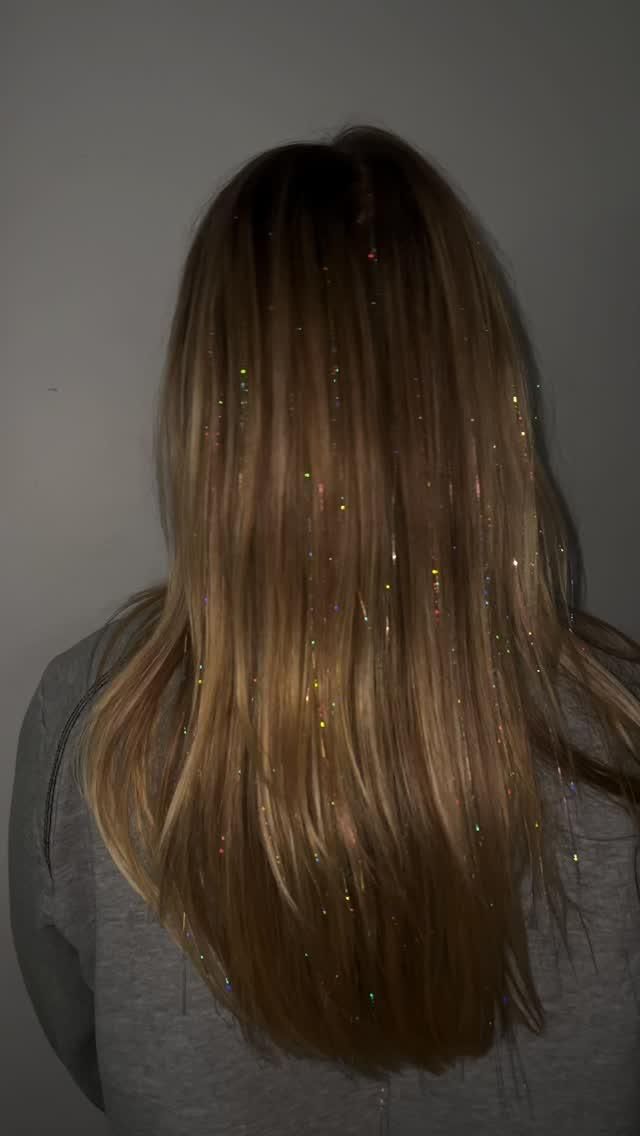 rainbow hair tinsel scattered through long blonde hair at home