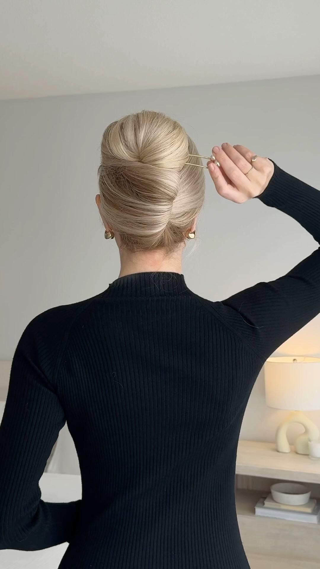 hand sliding a gold french pin into a blonde french twist