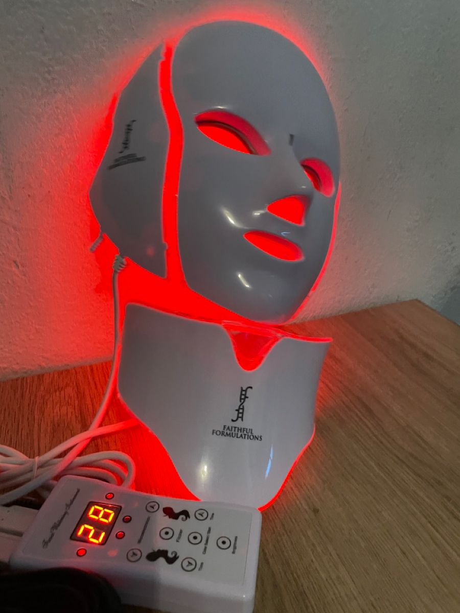 holding an LED red light therapy mask with remote timer