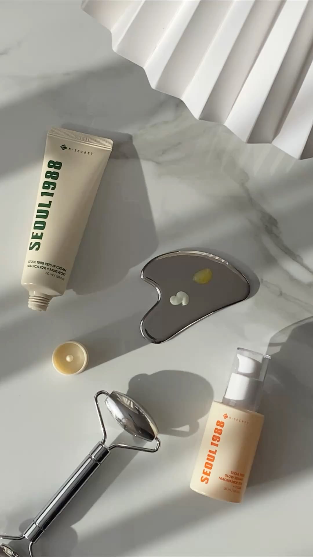 k-beauty skincare products with gua sha and face roller flat lay morning routine