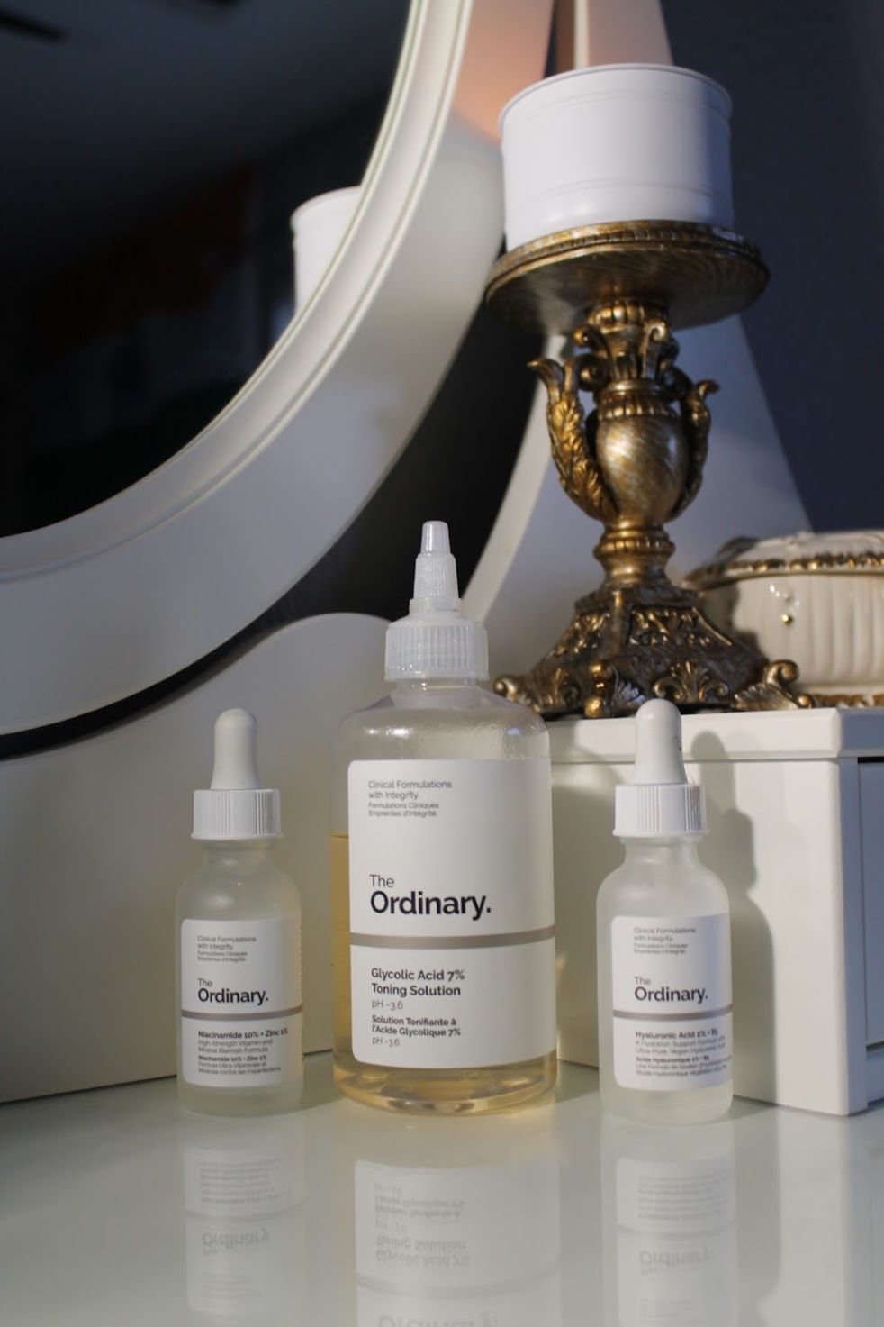 The Ordinary niacinamide and skincare products on a vanity with gold mirror