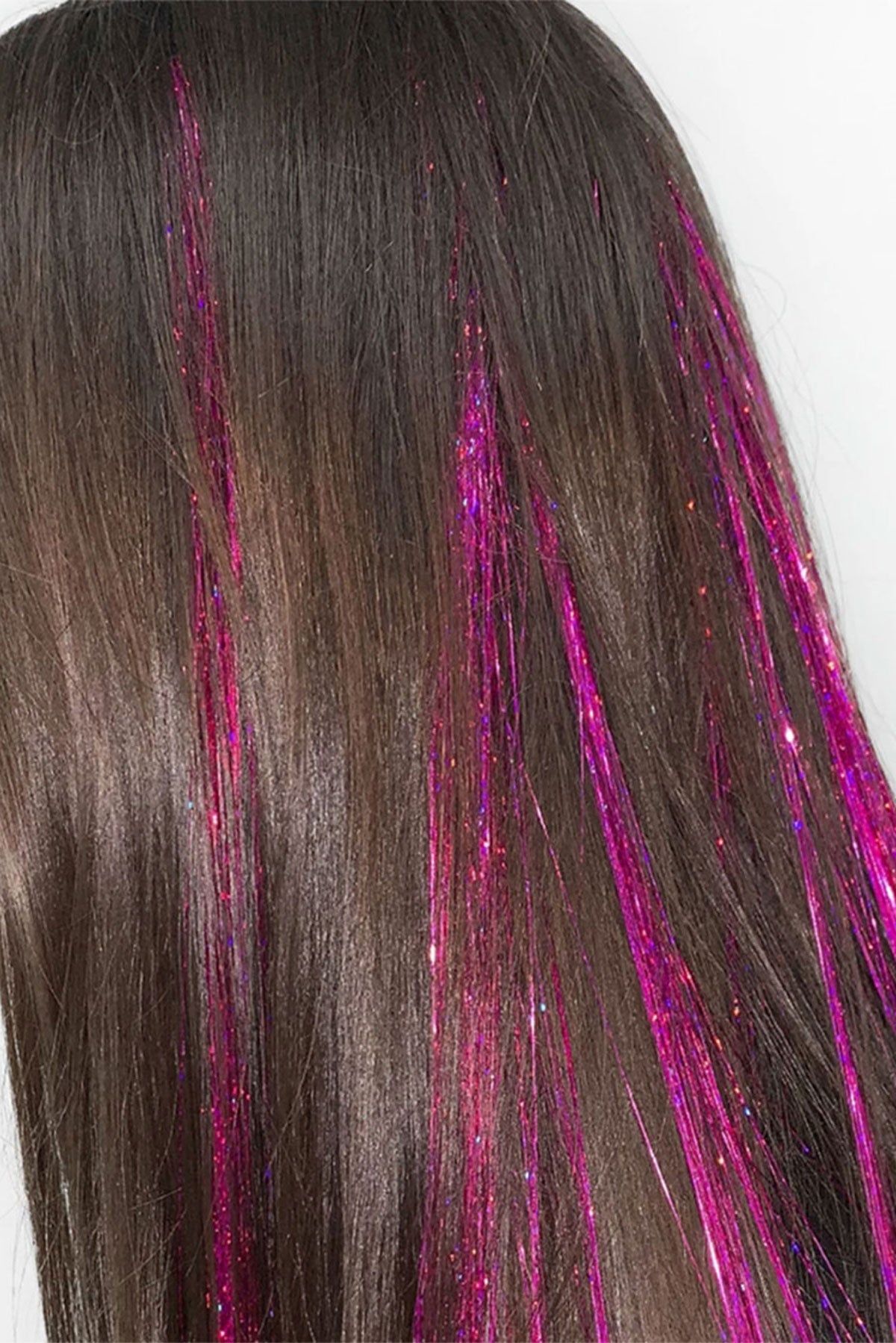 close up of hot pink hair tinsel strands tied into brown hair