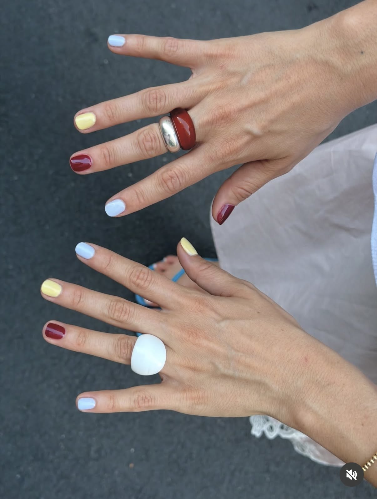 mismatched manicure with butter yellow, dark red, and pale blue nails in daylight