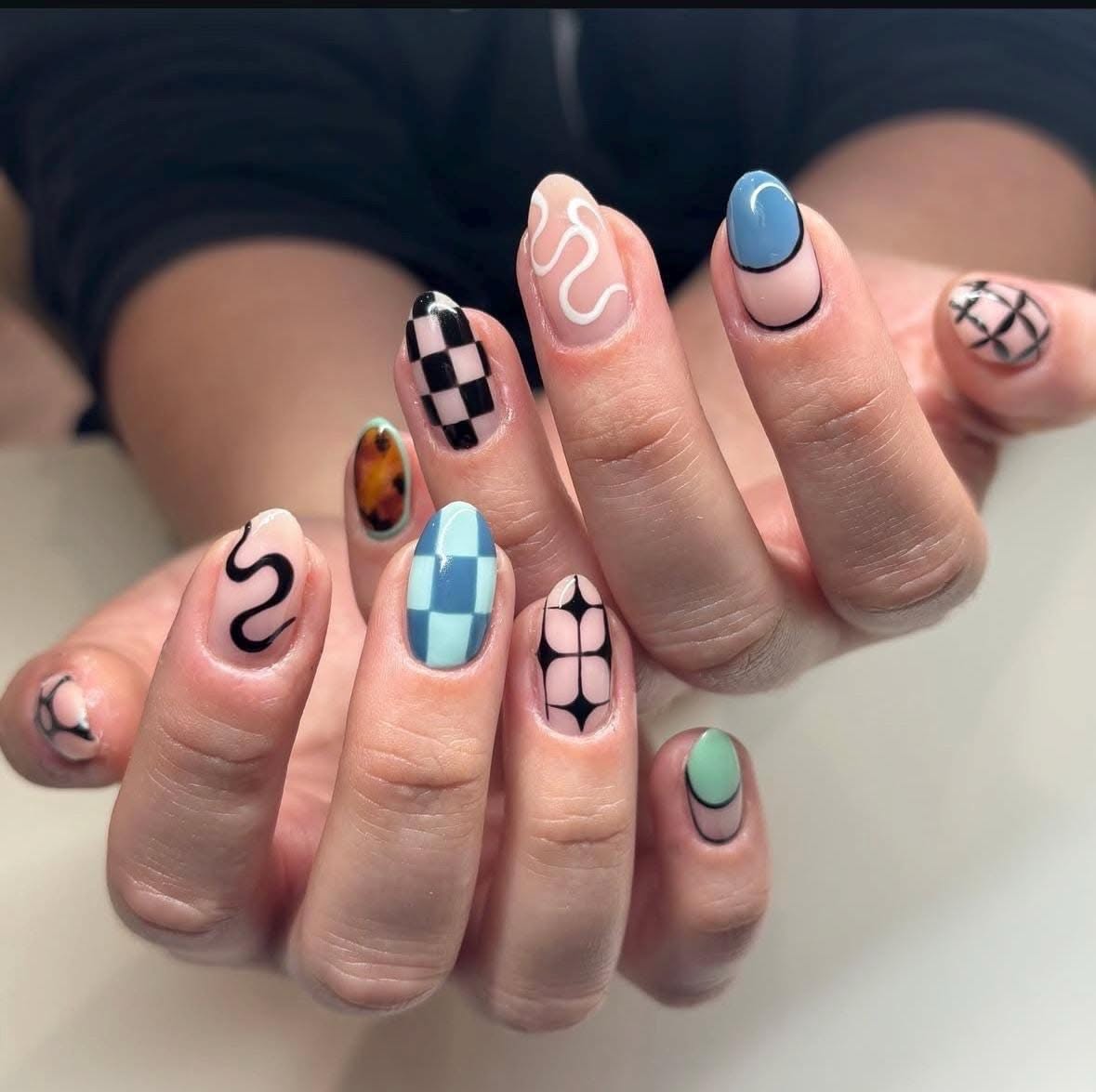mismatched nails mixing blue checkerboard, black swirls, and abstract art on a sheer base