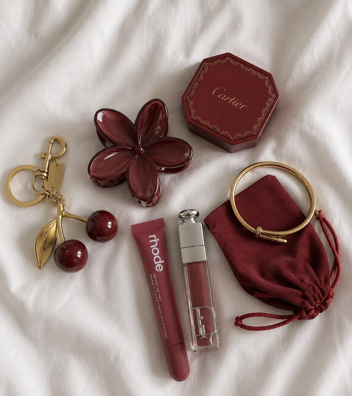 lip tint and beauty accessories flat lay on a bed
